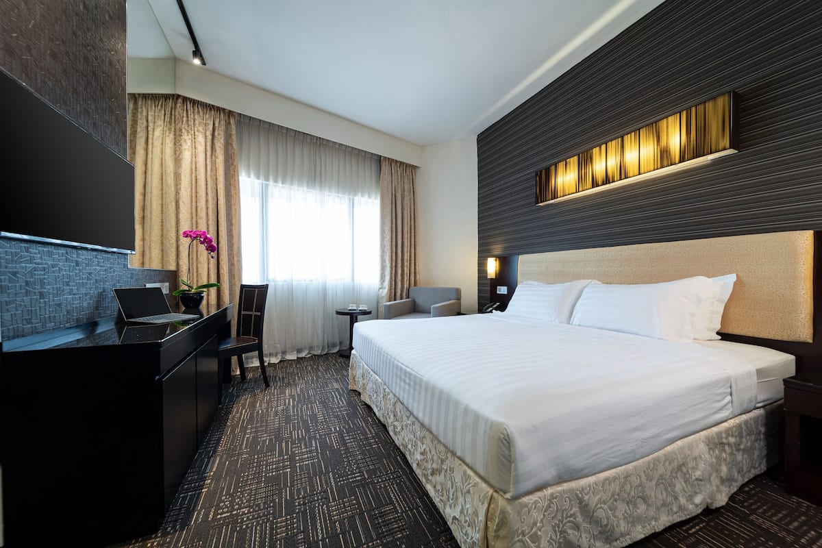 Une chambre d’hôtel avec un grand lit, un bureau avec un ordinateur portable, une petite table et une chaise.