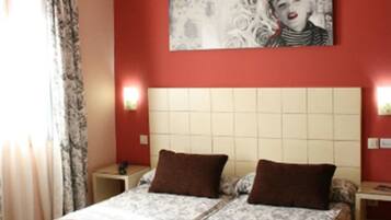 Una habitación de hotel con una cama grande, dos mesitas de noche y un cabecero.