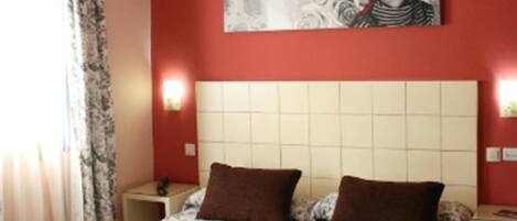 Una habitación de hotel con una cama grande, dos mesitas de noche y un cabecero.