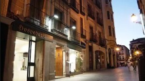Vista de una calle con un edificio que tiene una fachada con el letrero 'Hospedales'.