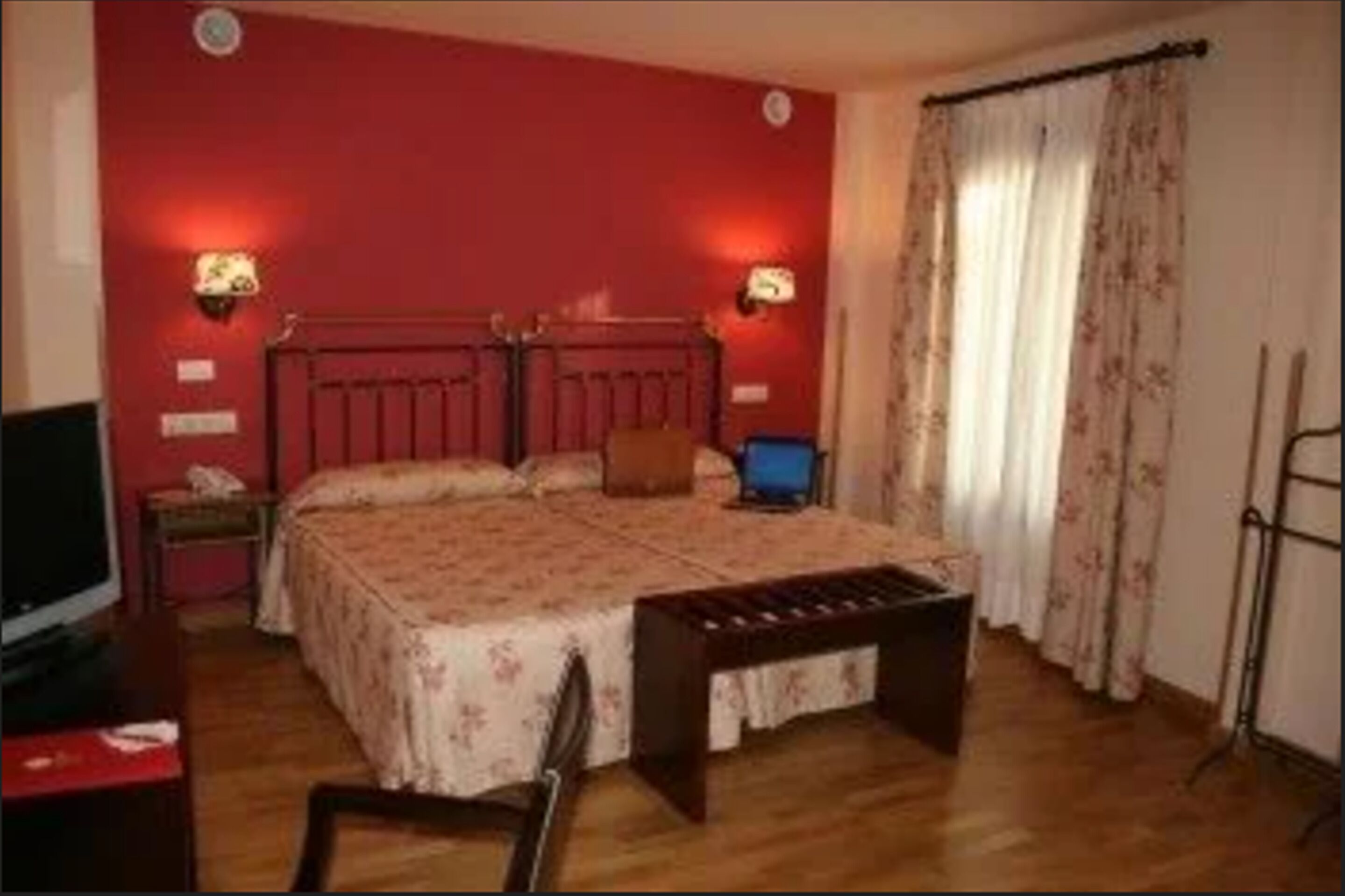 Un dormitorio con una cama de madera, dos mesitas de noche, un escritorio, una silla y un televisor.