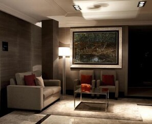 Een moderne woonkamer met een bank, fauteuils, een salontafel en een groot schilderij in een lijst aan de muur.