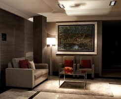 A modern living room with a sofa, armchairs, a coffee table, and a large framed painting on the wall.
