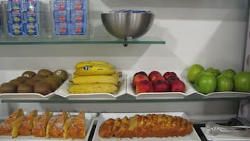 Eine Kühlvitrine mit verschiedenen Lebensmitteln, darunter Kiwis, Bananen, Pfirsiche und Äpfel.