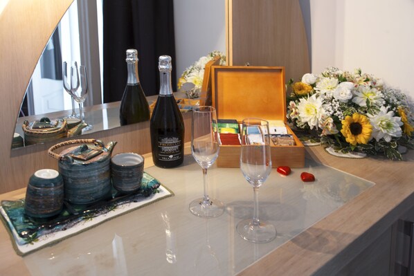 A well-organized bar area with a bottle of champagne, two wine glasses, a wooden box, and a floral arrangement.