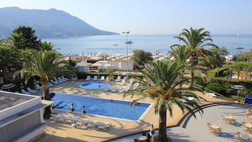 Una piscina techada, sombrillas, sillones reclinables de piscina