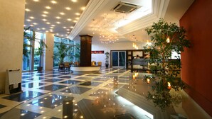 A spacious lobby with a checkered floor, large windows, and a central plant. - Hotel Montenegro Beach Resort (Becici)
