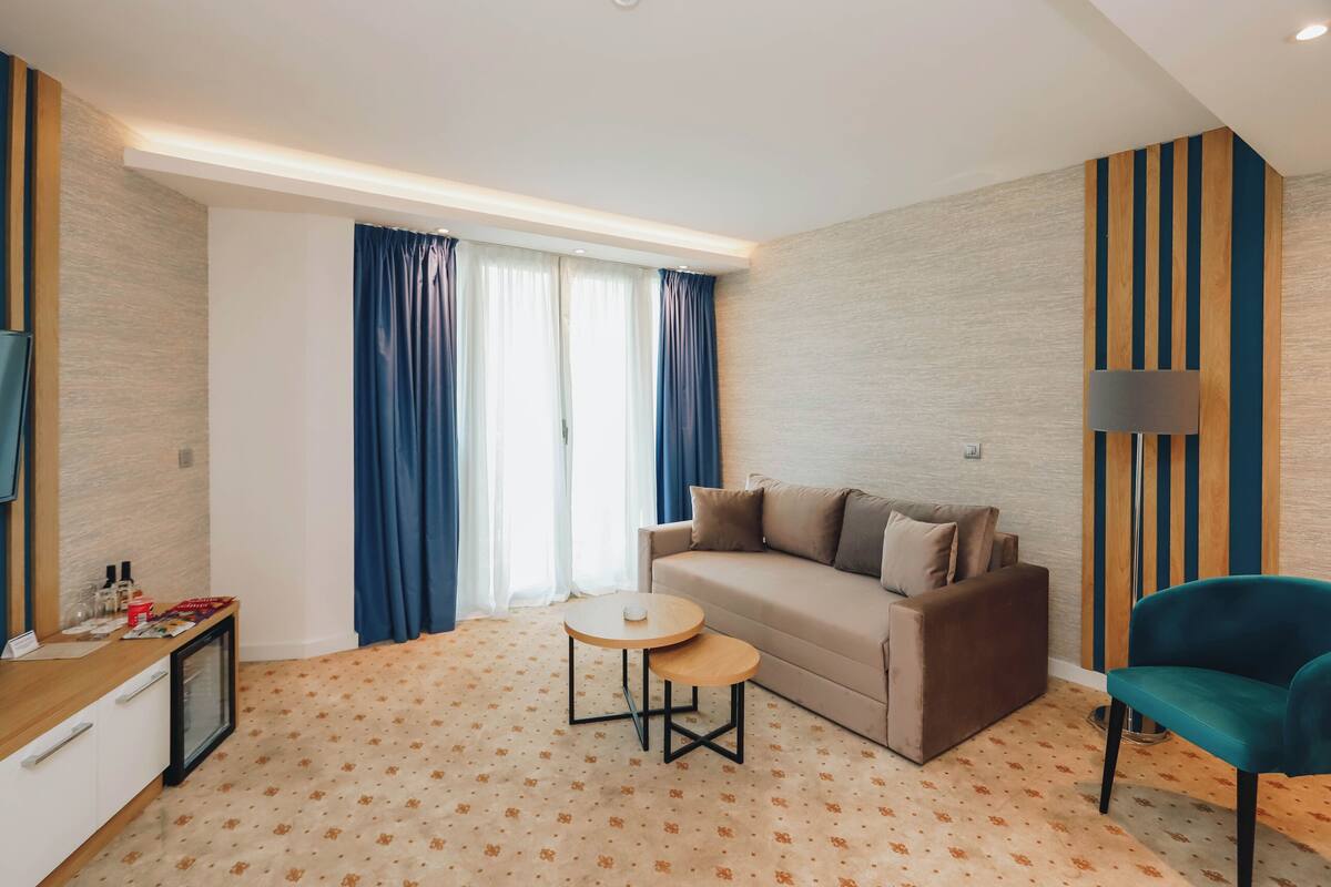 A modern living room with a sofa, a small round table, a TV, and a lamp.