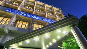 A hotel with a modern facade, multiple balconies, and a prominent illuminated sign. - Hotel Montenegro Beach Resort (Becici)
