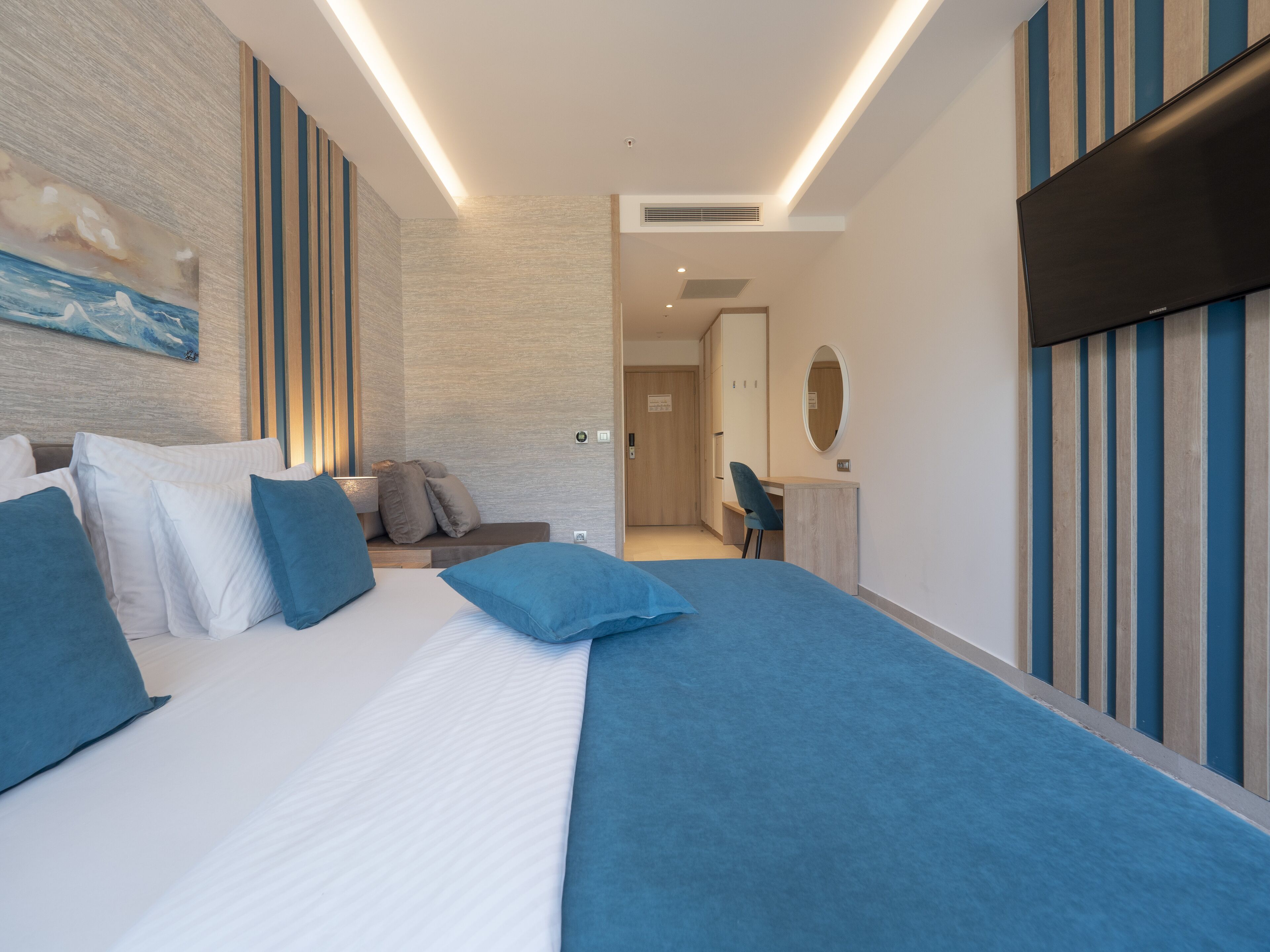 A modern hotel room with a large bed, a desk, and a seating area.