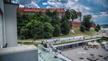 Ein Innenhof mit einem großen Gebäude im Hintergrund, umgeben von Bäumen und einem Gewässer.