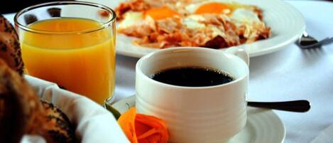 A breakfast setting with a glass of orange juice, a cup of coffee, and a plate of food.