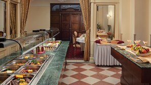 Ein Buffetbereich mit mehreren Speiseausgaben, einer Marmorplatte und einem Essbereich mit gedecktem Tisch für zwei Personen.