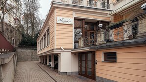Ein Gebäude mit einem Schild, auf dem „Alexander Restaurant“ steht, und einem überdachten Außenbereich für Sitzgelegenheiten.