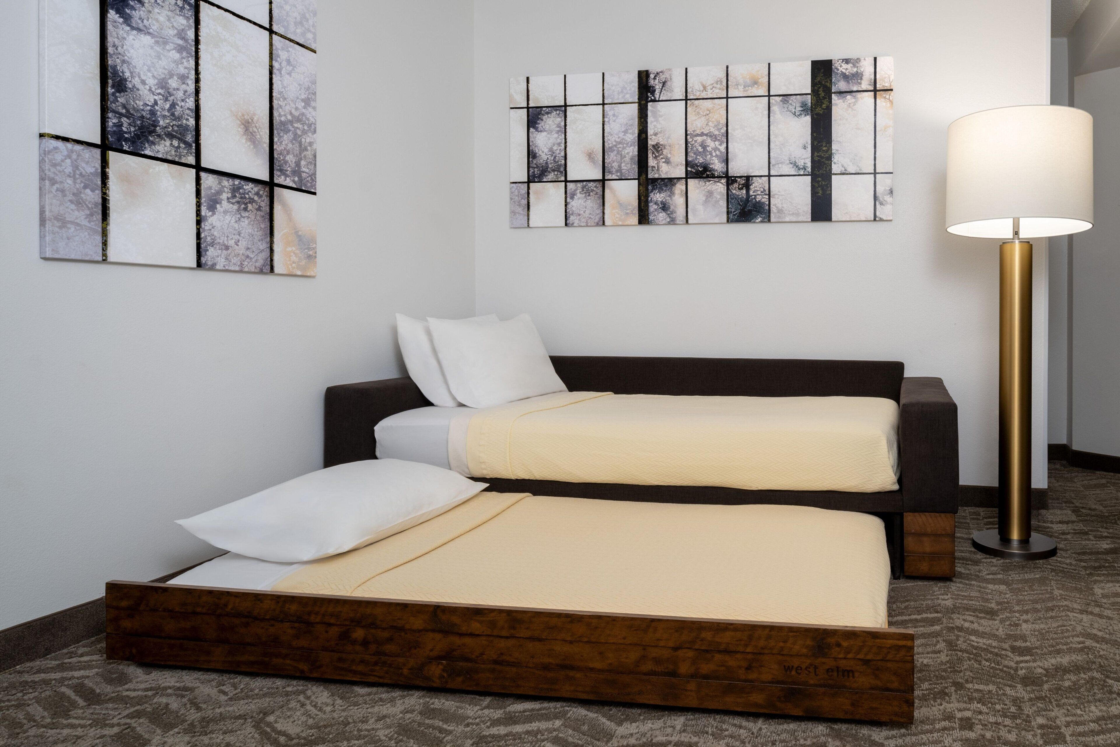 Una habitación de hotel con una cama, un sofá, una lámpara y arte abstracto en las paredes.