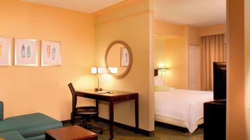 A hotel room with a bed, a desk with a chair, a television, and artwork on the wall.