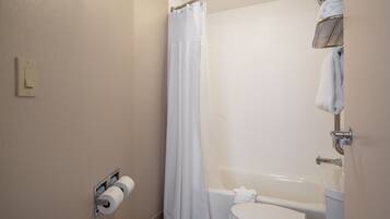 Un baño con inodoro, ducha con cortina, toallero y dispensador de papel higiénico.