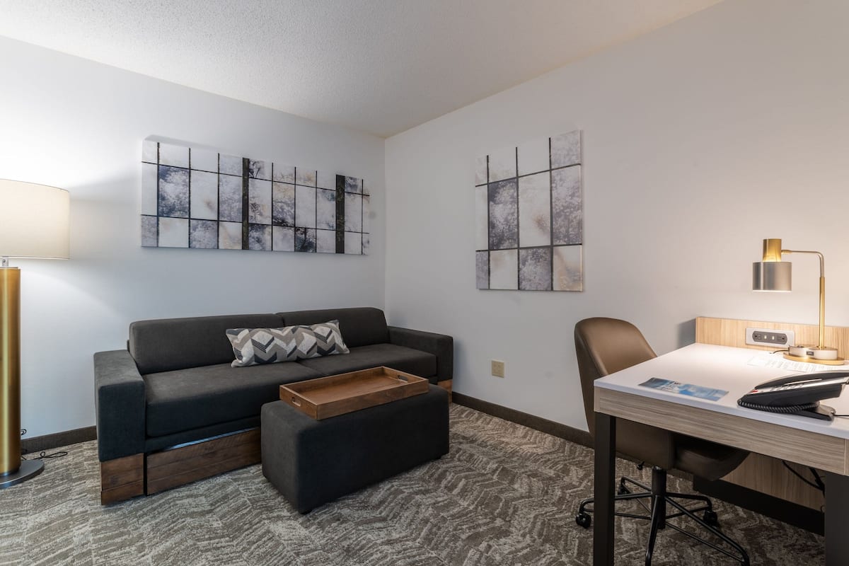 A modern room with a sofa, a desk, and two abstract wall art pieces.