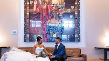 Un couple est assis sur un canapé dans une pièce où un grand tableau abstrait est accroché au mur.
