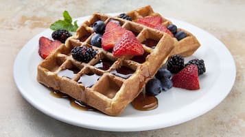 A plate of waffles with syrup and fresh berries.
