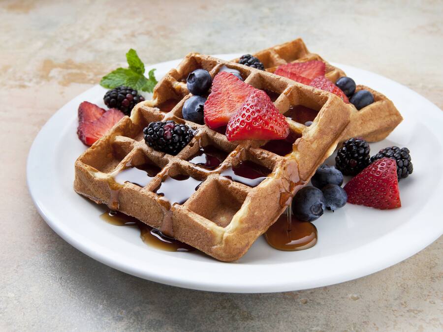 A plate of waffles with syrup and fresh berries.