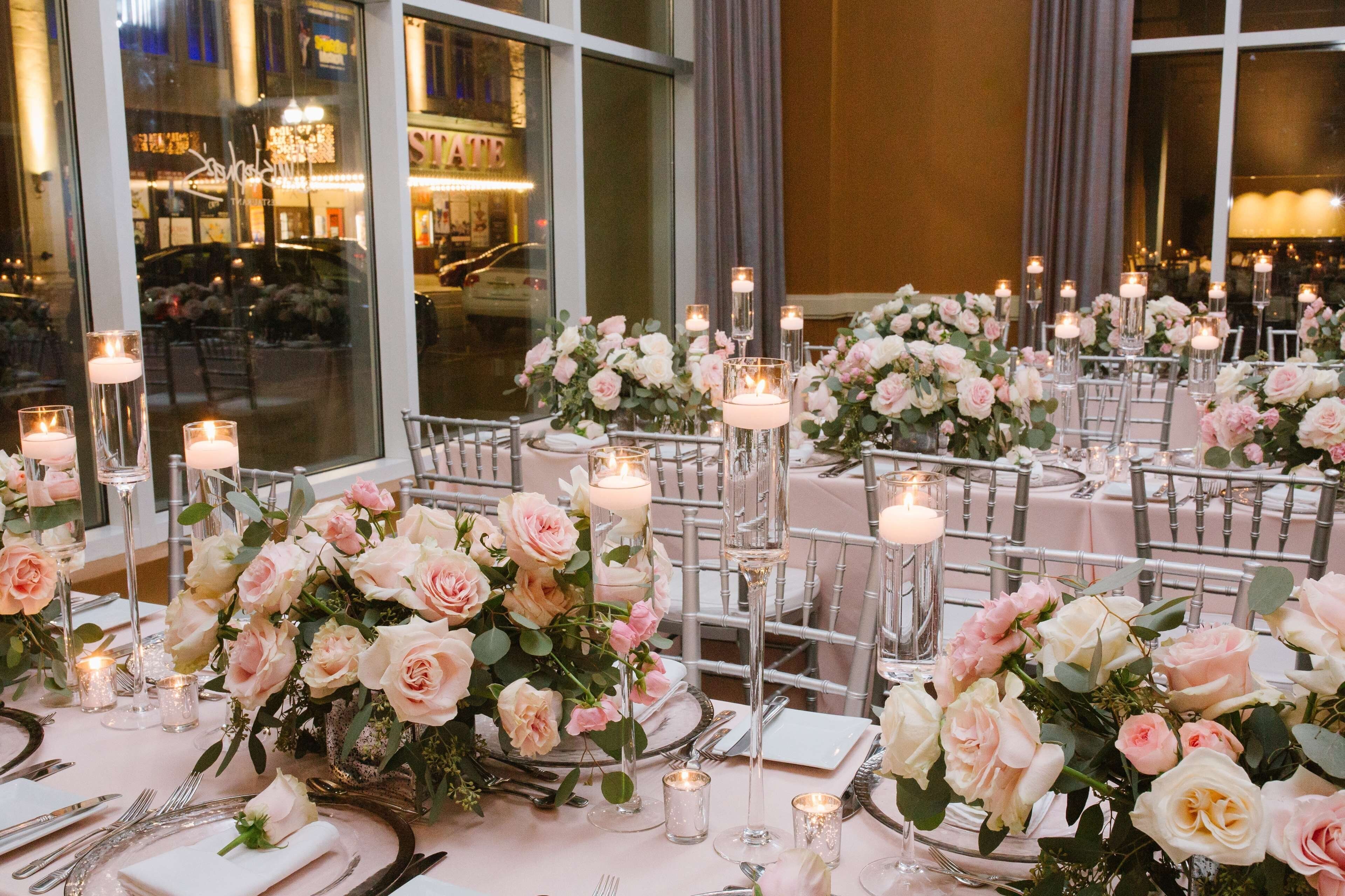 Une salle de banquet où les tables sont dressées pour un événement formel, avec des compositions florales et des bougies pour créer une ambiance chaleureuse.