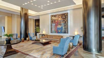 A modern lobby with a large abstract painting, a seating area with sofas and chairs, and a large metallic column.