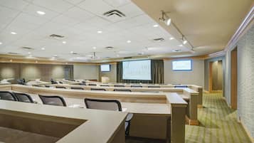 A conference room with a large screen displaying 'THE HELDRICH' and multiple rows of tables and chairs.