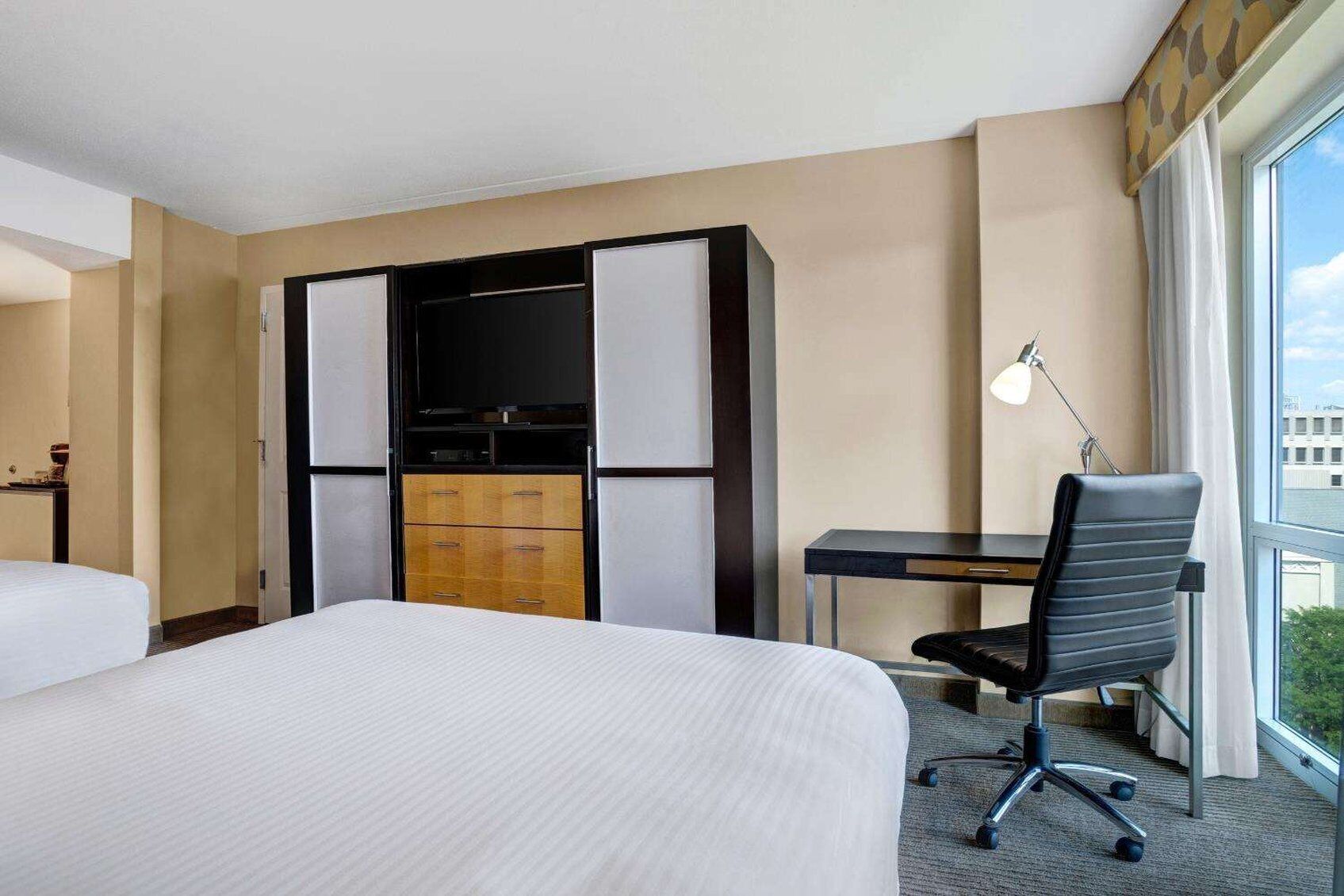 Ett hotellrum med en säng, ett skrivbord, en stol och en garderob.