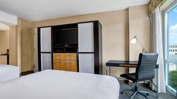 Ett hotellrum med en säng, ett skrivbord, en stol och en garderob.