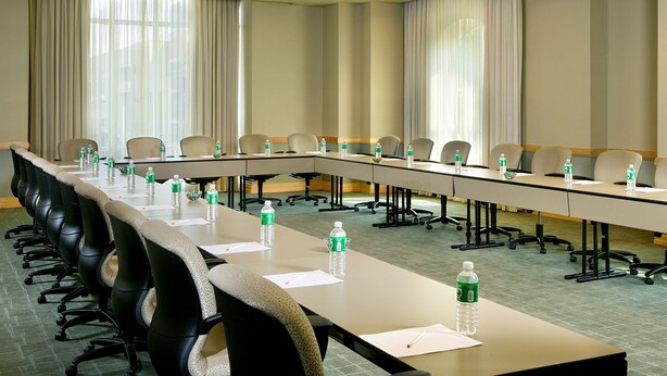 A conference room with a long table, chairs, water bottles, and a carpeted floor. - The Heldrich Hotel (New Brunswick)