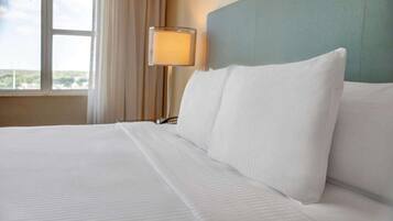 A hotel room with a large bed, a nightstand, a lamp, and a window with curtains.
