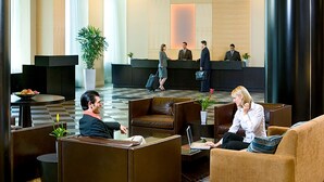Un hall d’hôtel comprenant un comptoir d’accueil, des espaces de détente et une grande plante.