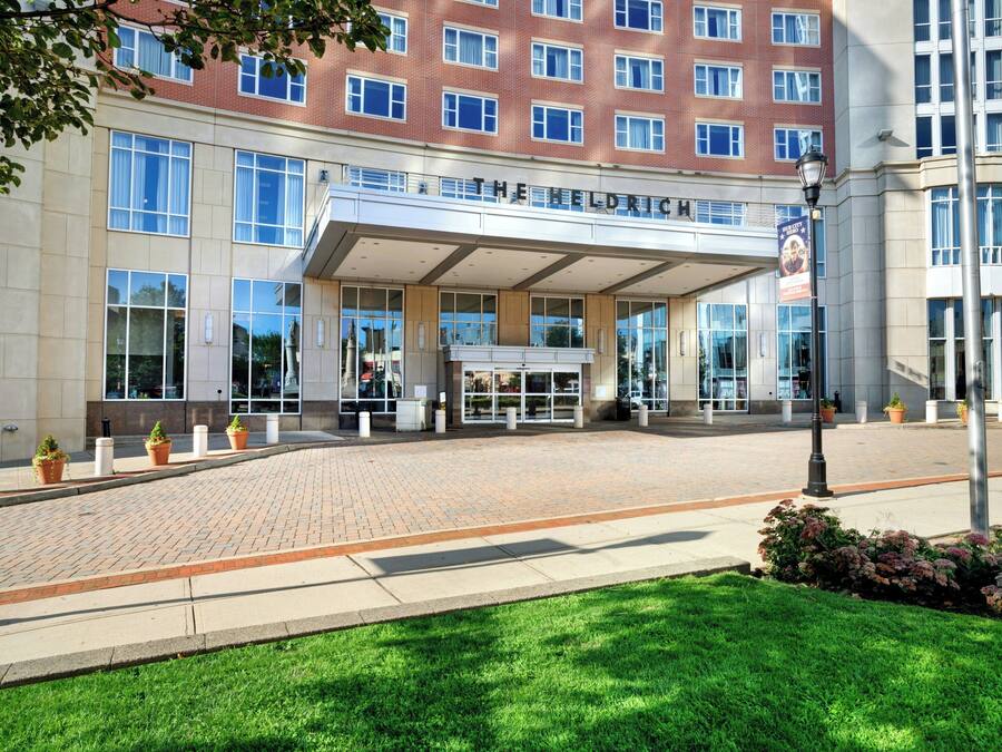 A multi-story hotel with a brick facade, large windows, and a covered entrance area.