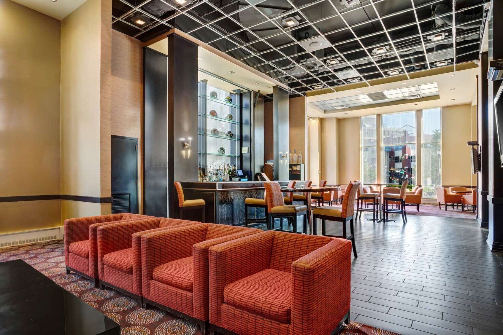 Un vestíbulo de hotel con zona de bar, áreas de descanso y vistas a través de amplios ventanales.