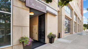 A building with a sign reading 'Christopher's Restaurant & Bar' and a door labeled 'Staff Only.' There are two potted plants on the sidewalk.