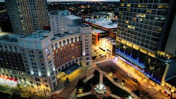 A cityscape with a prominent building featuring a central plaza with a fountain, surrounded by high-rise buildings.