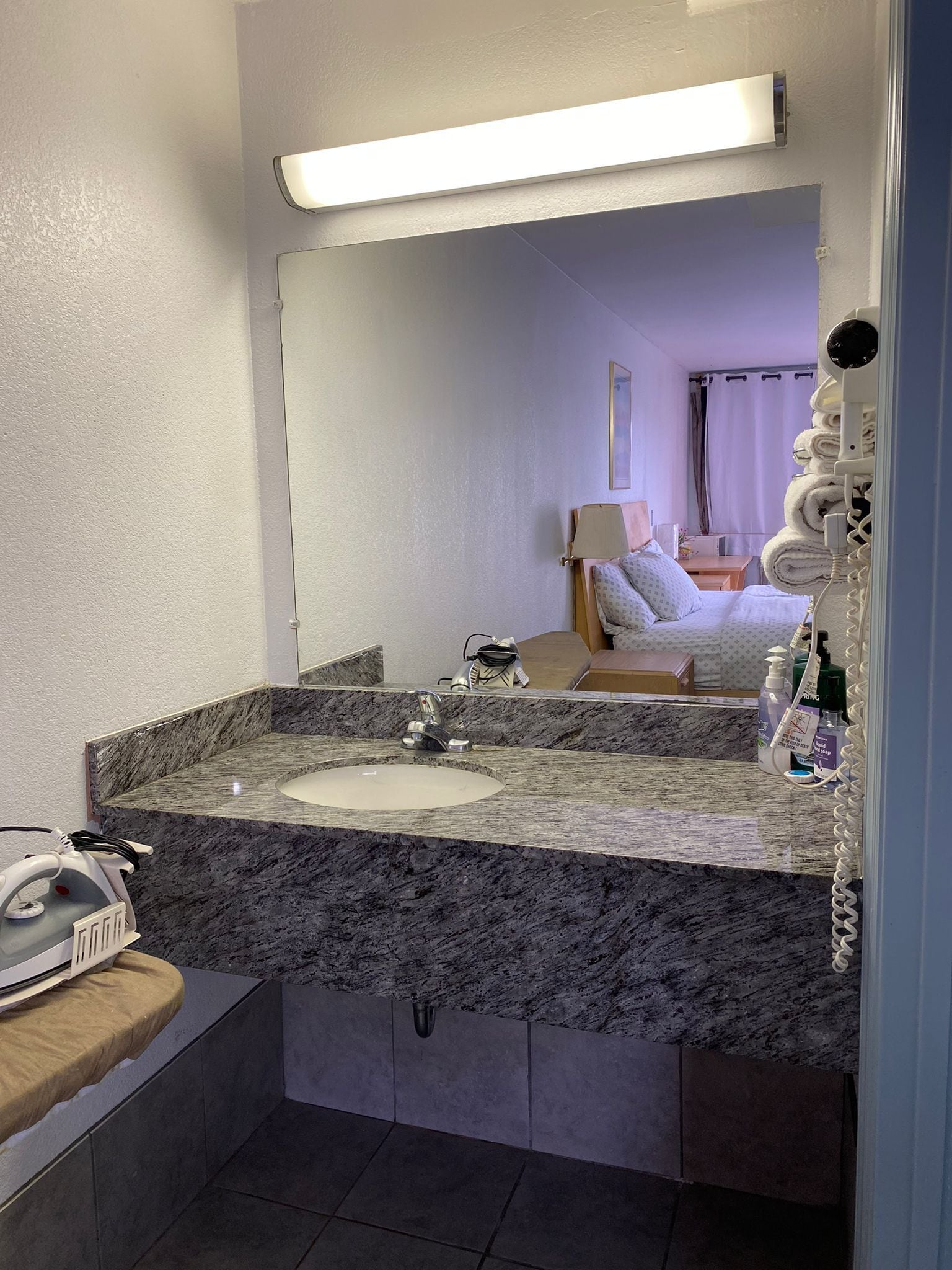 A bathroom with a marble sink, a mirror, and a towel rack.