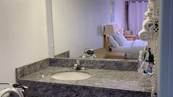 A bathroom with a marble sink, a mirror, and a towel rack.