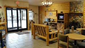 L’intérieur chaleureux d’un chalet avec une cheminée en pierre, des meubles en bois et un téléviseur.