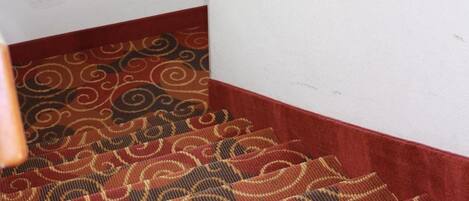 A carpeted staircase with a wooden handrail and a baseball bat hanging on the wall.