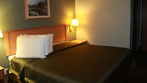 Une chambre d’hôtel avec un lit, une table de chevet, une lampe et un tableau encadré au mur.