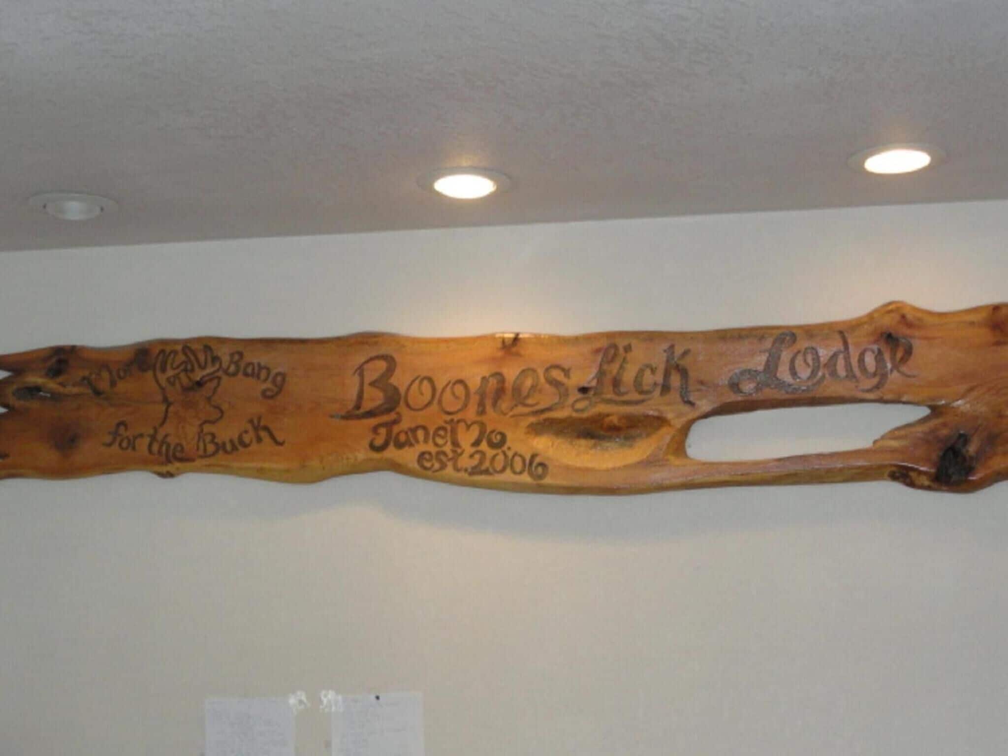 A wooden plaque with carved text and a cut-out section, mounted on a wall.