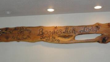 Una placa de madera con texto grabado y una sección recortada, montada en una pared.