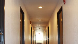 Un couloir d’hôtel avec un sol recouvert de moquette et des portes de part et d’autre.