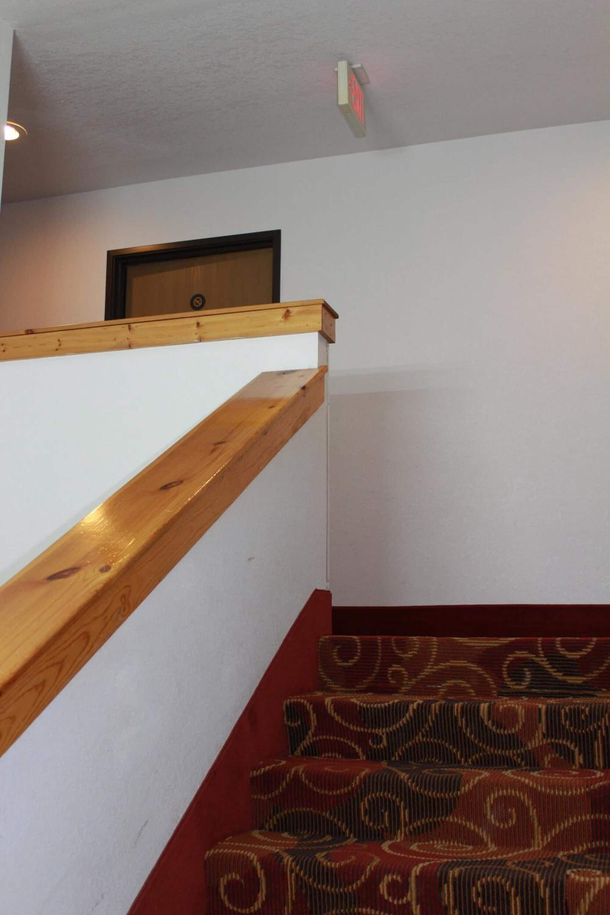Una escalera con barandilla de madera y alfombra estampada.
