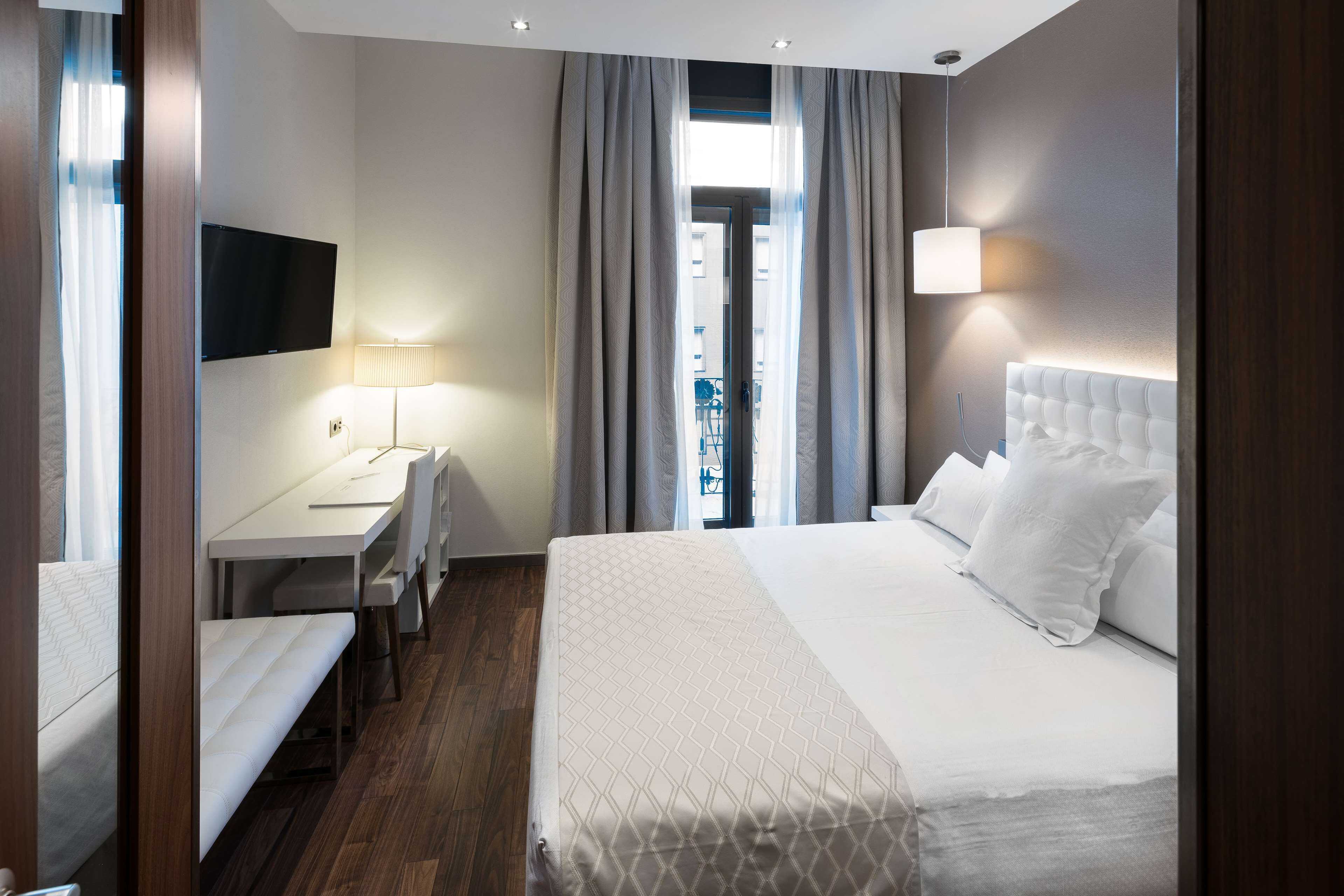 Una camera d'albergo con un letto, una scrivania e una televisione.