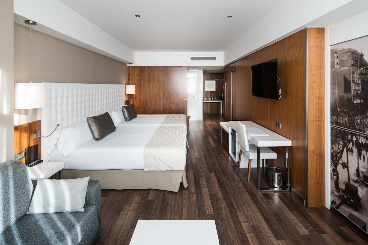 A modern hotel room with a large bed, a desk, and a TV.