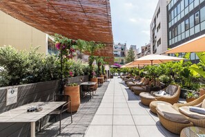 An outdoor patio area with seating arrangements, potted plants, and a tiled floor. - Catalonia Ramblas (Barcelona)