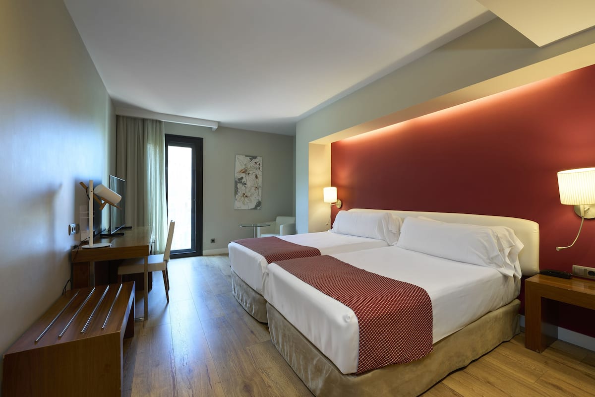 A hotel room with a large bed, a desk, and a chair.